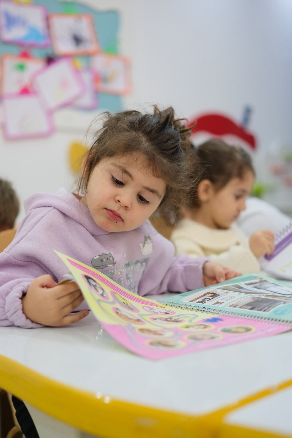 Sınıfta çalışma kitabını inceleyen okul öncesi çocuk