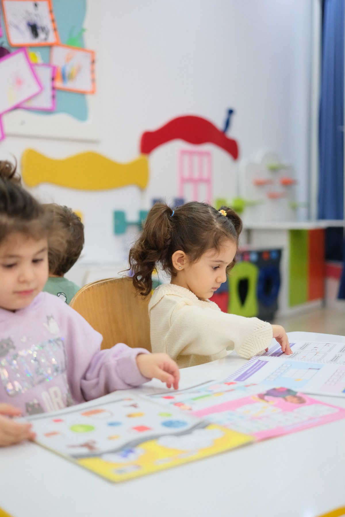 Aydınlık sınıfta çalışma kitaplarıyla etkinliğe katılan çocuklar
