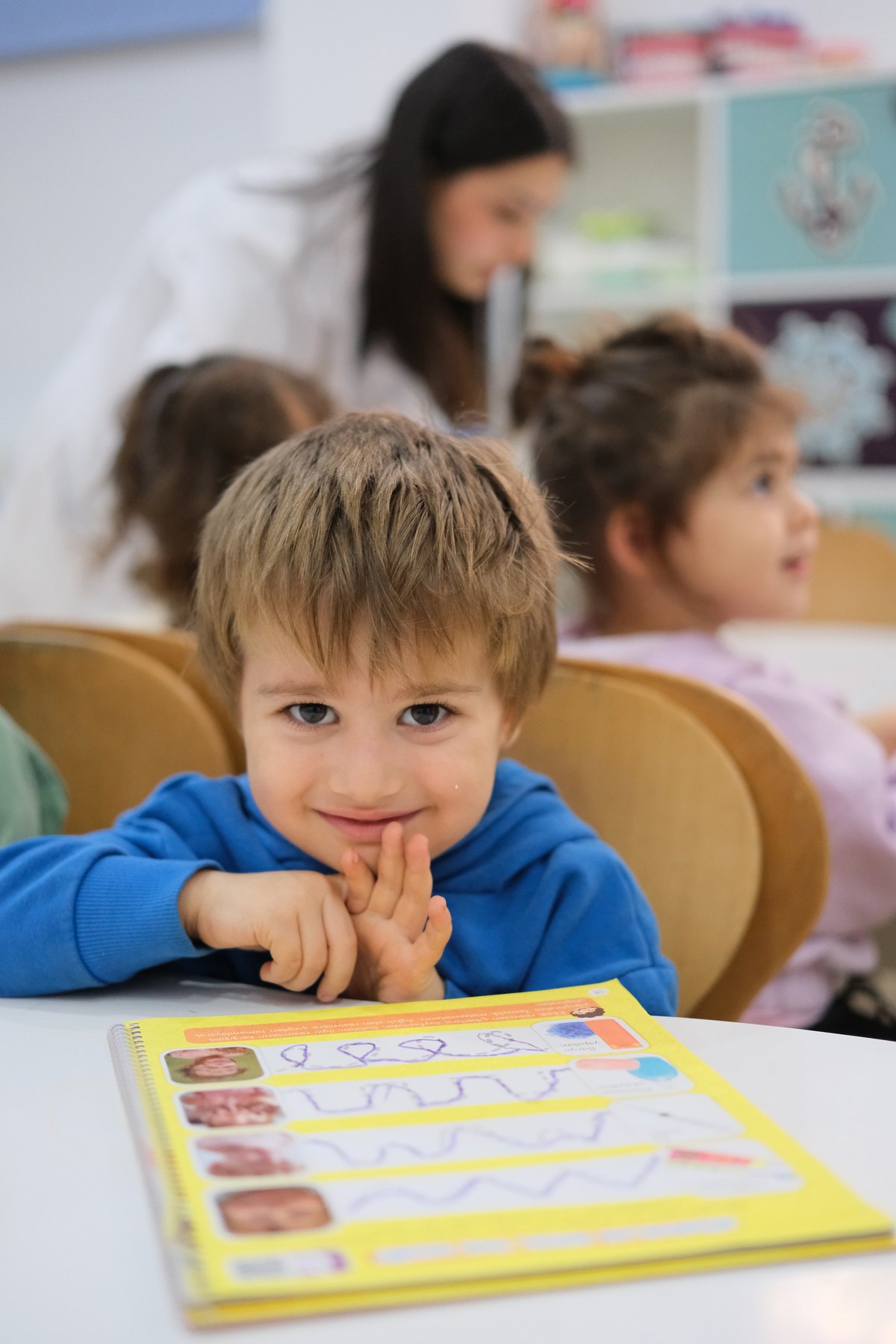 Sınıfta çalışma kitabıyla etkinliğe katılan okul öncesi çocuk